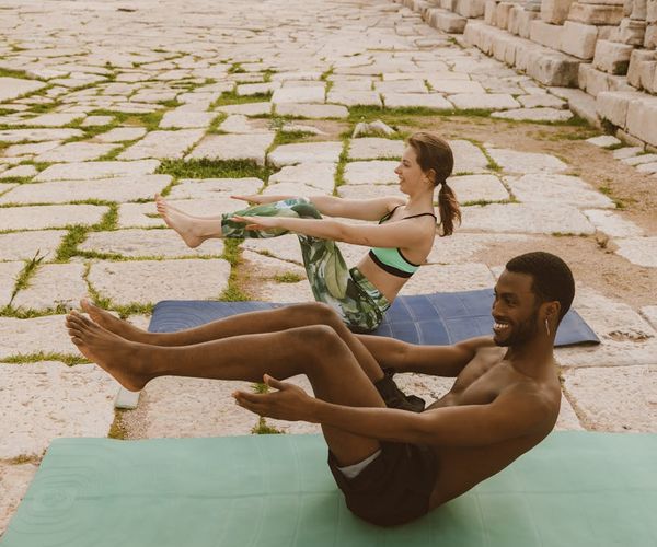 Diverse group of people smiling during a light yoga session outdoors.
