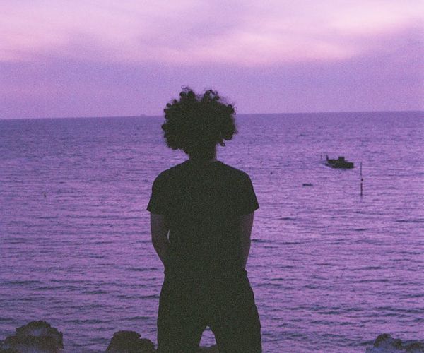 Person meditating peacefully at sunrise with a calm landscape background.